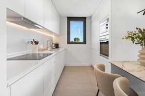 Eine moderne Küche mit weißen Schränken, einer schwarzen Arbeitsplatte, einem Fenster und einer Marmor-Spritzschutzwand.