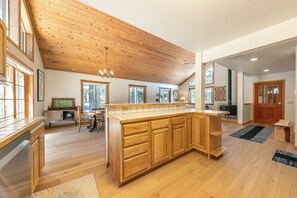 Eine geräumige Küche mit Holzschnitzereien, einer großen Kochinsel und einer hohen Decke mit freiliegenden Balken.