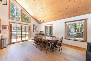 Un'ampia sala da pranzo con un grande tavolo e sedie in legno, ampie finestre e soffitto in legno.