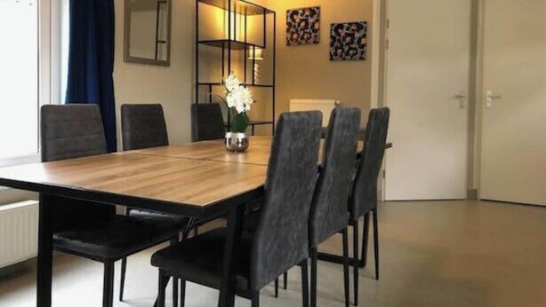 A dining area with a wooden table, black chairs, a vase with flowers, and a modern lamp. - Holiday Home in Amstelveen With Terrace (Amstelveen)