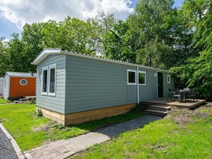 Een kleine, gelijkvloerse stacaravan met een voortuin en een klein terras.