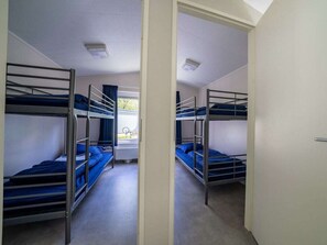 Een kamer met stapelbedden, een raam met gordijnen en een radiator.