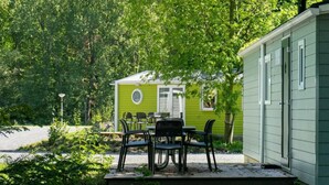A green mobile home with a patio area, outdoor seating, and a bicycle. - Holiday Home in Amstelveen With Terrace (Amstelveen)