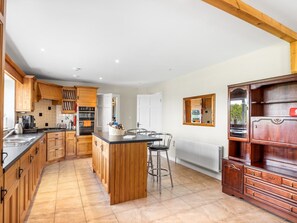 Eine Küche mit Holzausstattung, einer zentralen Kochinsel, Barhocker und einem eingebauten Schrank mit Schubladen.
