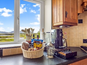 Eine Küche mit Kaffeemaschine, einer Snackauswahl und Blick ins Freie.