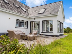 Ein modernes Haus mit Terrasse, zwei Sofas und einem Esstisch.