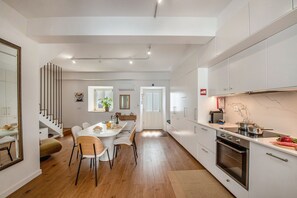Eine moderne Küche mit weißen Schränken, einem eingebauten Backofen und einem Essbereich mit weißem Tisch und Stühlen.