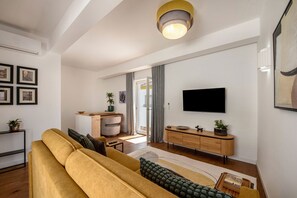 Ein modernes Wohnzimmer mit einer Couch, einem Fernseher und einer Holzkommode.