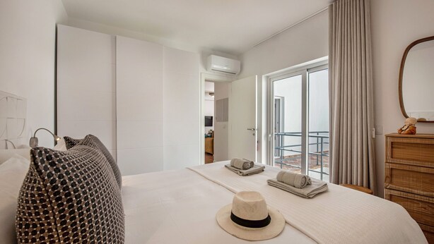 Een hotelkamer met een groot bed, een raam met gordijnen, een houten dressoir en een airconditioning.