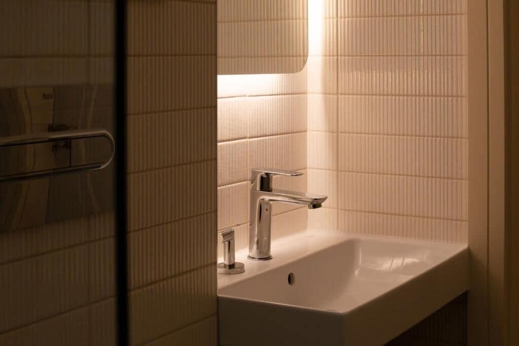 A bathroom with a white sink, a mirror, and a towel rack.