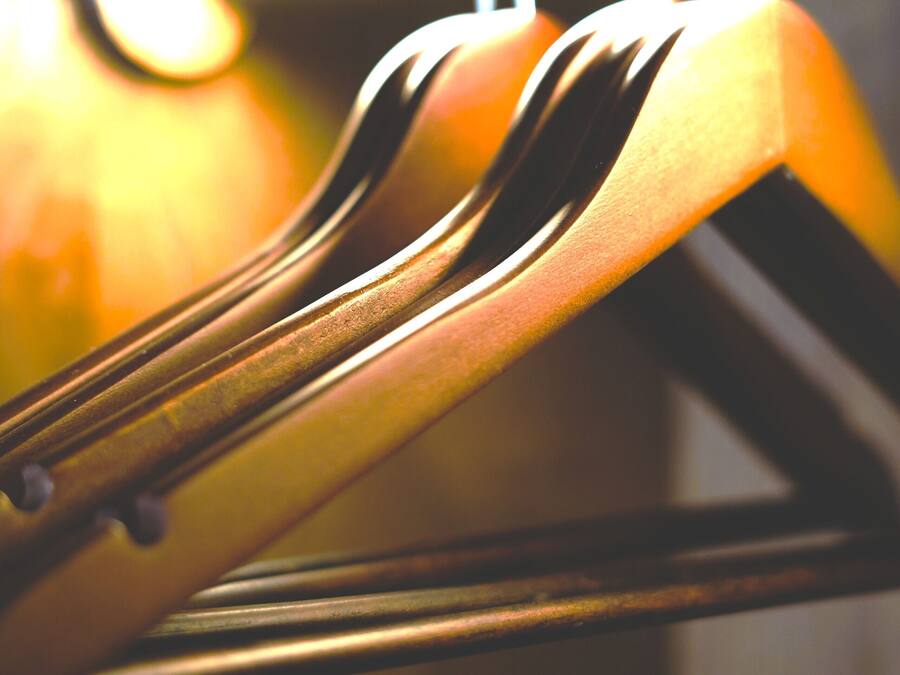 A close-up of a wooden hanger with a metal hook.