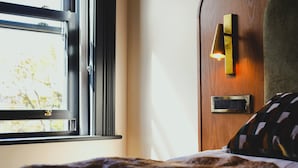 Una habitación con ventana, una lámpara de pared y un enchufe.