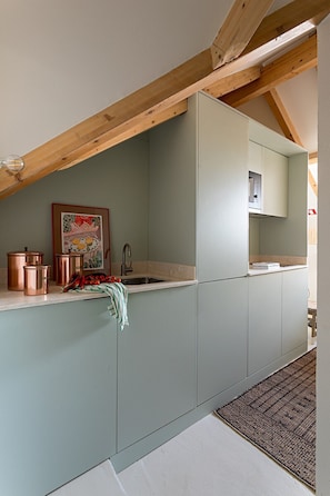 Eine Küche mit Kupfergeschirr, einem Spülbecken und einem Holzbalken an der Decke.
