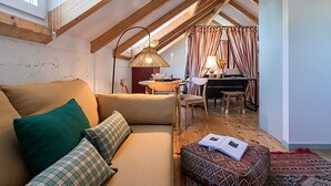 Een gezellig loft slaapkamer met schuine wand, een bank, een bureau en een eethoek.
