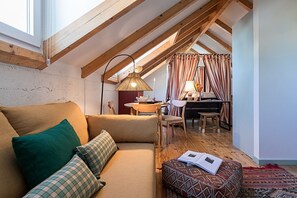 A cozy loft bedroom with a sloped ceiling, a sofa, a desk, and a dining area. - The Old Net Studio in Porto Brandão (Caparica)