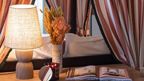 Een gezellige kamer met een houten bureau, een lamp, een vaas met gedroogde bloemen, een kaars en een tijdschrift.