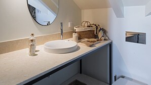 Een moderne badkamer met een ronde spiegel, een wastafel en een toilet.