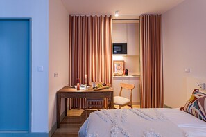 Ein Schlafzimmer mit Bett, Schreibtisch, Stuhl und einer Küchenzeile.