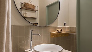 A bathroom with a round mirror, a sink, and a towel rack. - Tanoeiro's Cottage in Porto Brandão (Caparica)