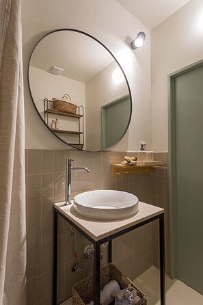 Ein Badezimmer mit rundem Spiegel, Waschbecken und Handtuchhalter.