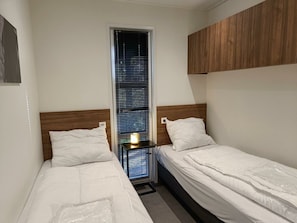 A small, clean room with two single beds, a window with blinds, and a wooden headboard. - Holiday Home in Otterlo With Terrace (Otterlo)