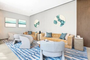 Ein modernes Wohnzimmer mit einer Couch, Sesseln und Kunstwerken an den Wänden.