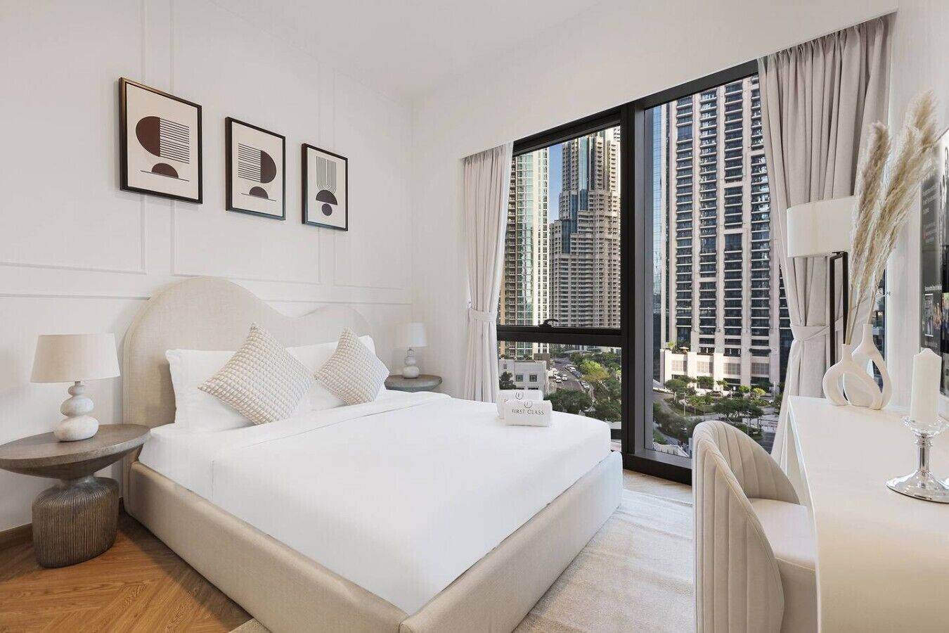 A modern hotel room with a large bed, a desk, and a view of tall buildings.