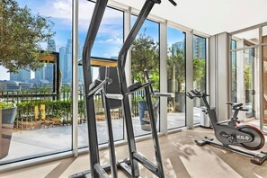 Ein modernes Fitnessstudio mit Trainingsgeräten, großen Fenstern und Blick auf die Stadt.