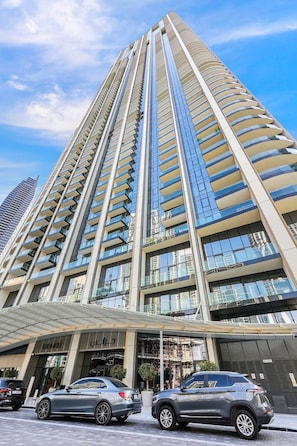 A high-rise building with a modern architectural design, featuring a prominent glass facade and a series of balconies. - FIRST CLASS 2BR Next to Burj Khalifa & Dubai Mall (Downtown)
