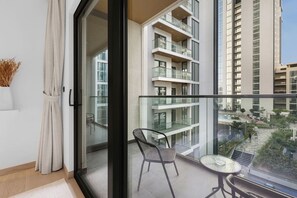 A modern apartment with a balcony, a glass door, and a view of other buildings. - FIRST CLASS | 1BR | Contemporary Meydan Living (Meydan)