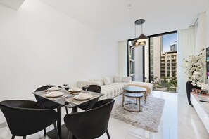 A modern living room with a dining area, large windows, and a view of the city. - FIRST CLASS | 1BR | Contemporary Meydan Living (Meydan)