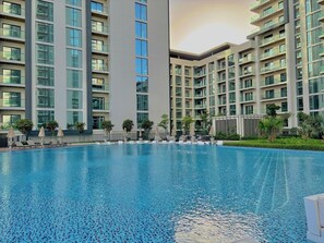 A modern hotel with a swimming pool, multiple balconies, and a well-maintained garden area. - FIRST CLASS | 1BR | Contemporary Meydan Living (Meydan)