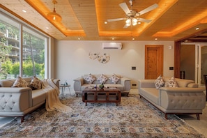 A living room with two sofas, a coffee table, and a patterned rug. - ELIVAAS Bask and Blessings Meadows 3BHK (Anhech)