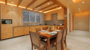Una cocina con armarios de madera, una mesa de comedor con sillas y una ventana con adornos de platos.