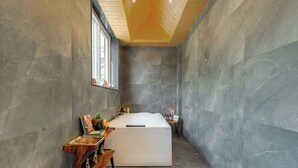 Un baño moderno con una bañera independiente, un tocador de madera y un ventanal que permite la entrada de luz natural.