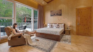 Un dormitorio con un ventanal grande, una cama, un chaise-lounge y techo de madera.