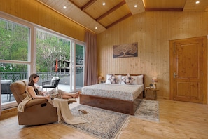 A bedroom with a large window, a bed, a chaise lounge, and a wooden ceiling. - ELIVAAS Bask and Blessings Meadows 3BHK (Anhech)