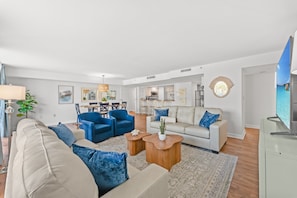 Ein modernes Wohnzimmer mit einer Couch, Sesseln, einem Couchtisch und einem Fernseher.