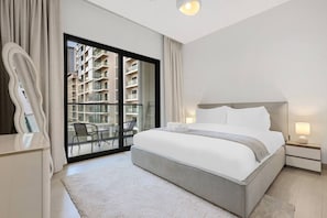 A modern hotel room with a large bed, a balcony with chairs, and a view of a high-rise building. - FIRST CLASS | 1BR | Chic Glimpse Near Downtown (Meydan)