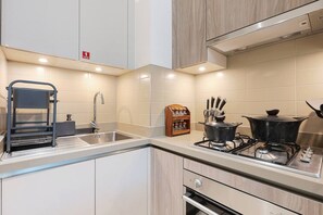 A modern kitchen with a sink, stove, and cabinets. - FIRST CLASS | 1BR | Chic Glimpse Near Downtown (Meydan)