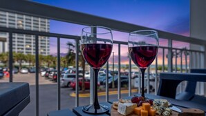 Ein Balkon mit Tisch, gedeckt mit zwei Weingläsern und einer Holzplanke mit Käse und Trauben.