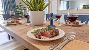 Ein Esstisch mit einem Steak, Weingläsern und einer Topfpflanze.