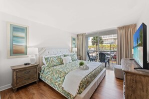 A hotel room with a bed, a nightstand, a TV, and a balcony with a table and chairs. - $150 Free activities - E-gift card when you book- On the ocean | SH105-2 (Myrtle Beach)