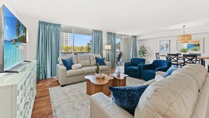 Ein modernes Wohnzimmer mit einer Couch, Sesseln, einem Couchtisch und einem Essbereich mit Tisch und Stühlen.
