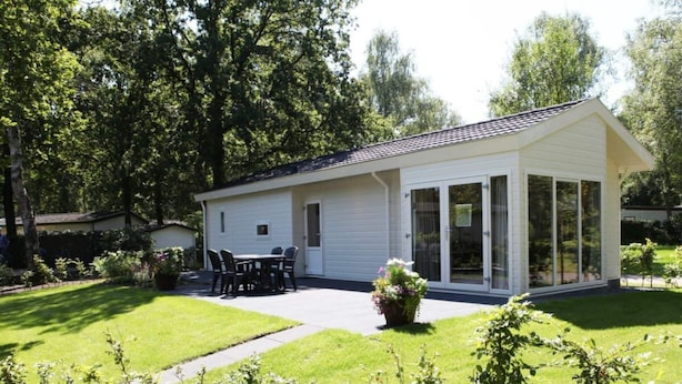 Ett enplanshus med en uteplats, ett matbord och stolar.
