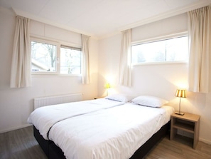 A bedroom with a large bed, two bedside lamps, a window, and a radiator. - Holiday Home in Arnhem With Terrace (Arnhem)