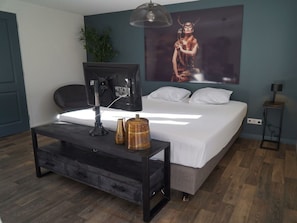 Ein Schlafzimmer mit einem Bett, einem Schreibtisch mit Computer, einer Lampe und einem Bild an der Wand.