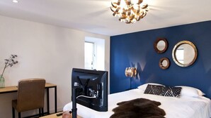 A bedroom with a bed, a desk, a chair, a television, and a decorative mirror. - Comfort Room Deluxe 2 (Otterlo)