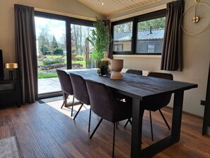 Een eetgedeelte met een donker houten tafel, vier stoelen en een potplant.
