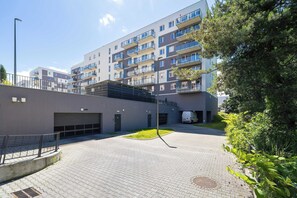 En moderne, flereetagers boligbygning med altaner, en belagt gårdsplads og indkørsel til garage.